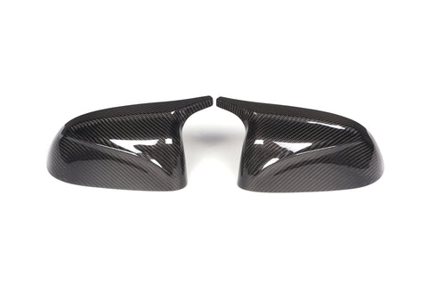 Two carbon fiber side mirror covers are positioned side by side, slightly angled inward, on a plain white background, showcasing their glossy, textured surfaces.