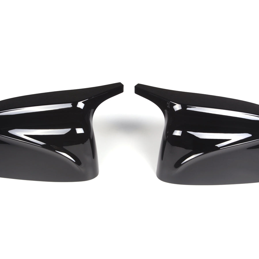 Two glossy black car mirror covers facing each other on a white background, showcasing sleek design and smooth, reflective surfaces.