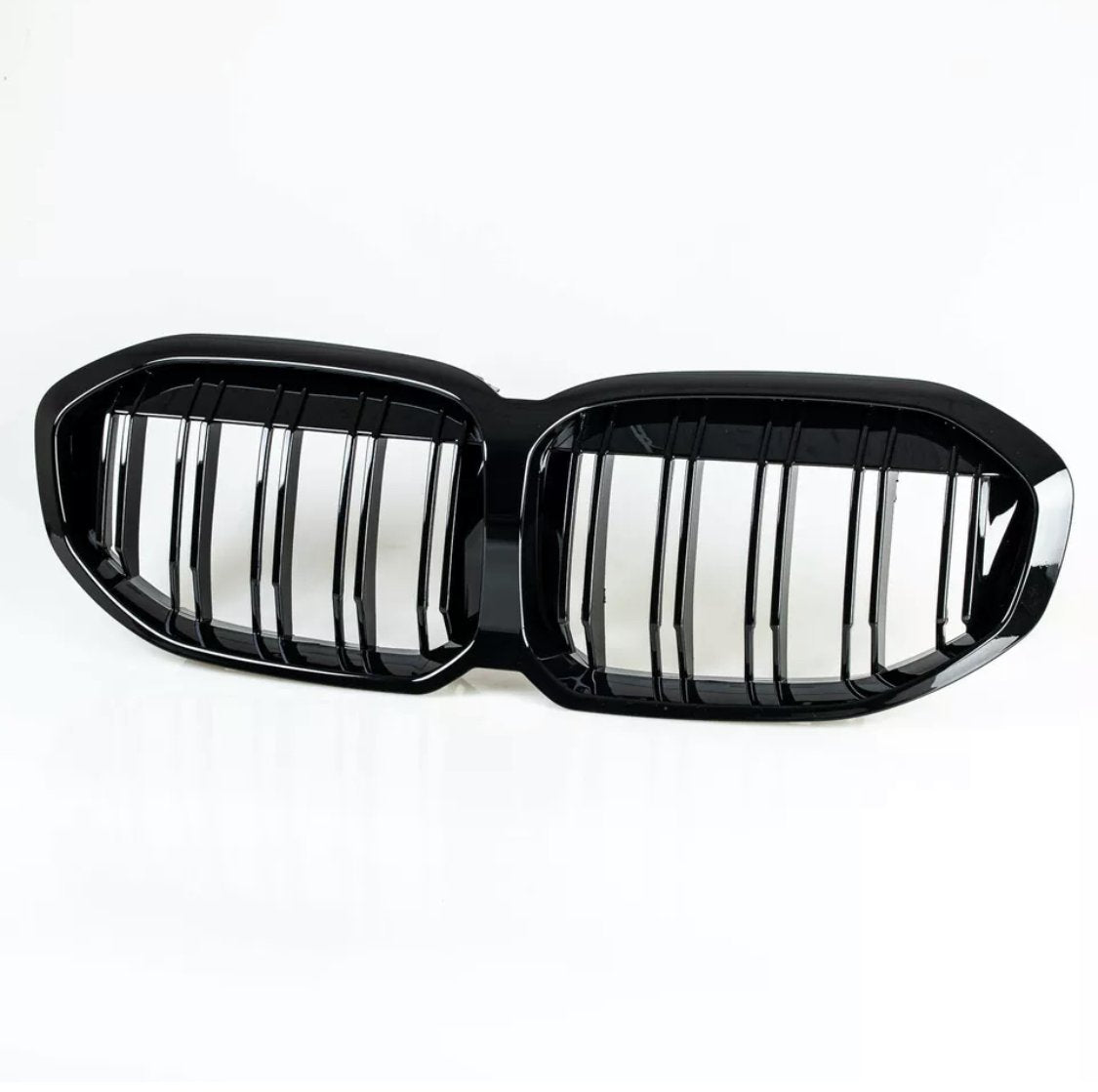 A black dual-section car grille, featuring vertical slats, is resting on a white background.