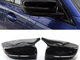Car side mirror, sleek black design, attached to a blue vehicle. Below, two detached mirror covers on a white surface, emphasizing their glossy finish and aerodynamic shape.