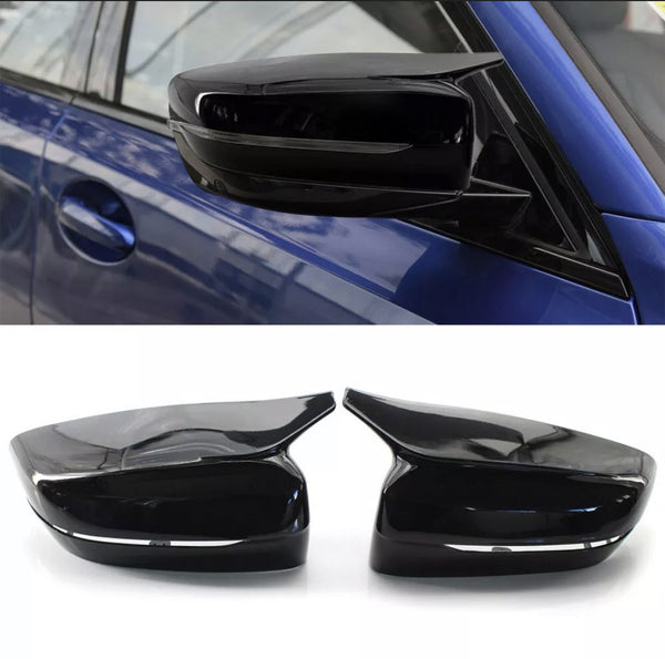 Car side mirror, sleek black design, attached to a blue vehicle. Below, two detached mirror covers on a white surface, emphasizing their glossy finish and aerodynamic shape.