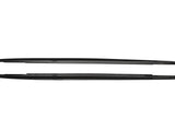 Two sleek, black car side skirts, aligned horizontally, lie against a plain white background, showing their aerodynamic design and smooth edges.