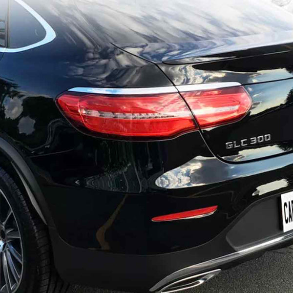 A black car is parked in a lot, reflecting clouds. The license plate reads "CARBON ACCENTS." The model text "GLC 300" and "4MATIC" appears on the rear.