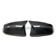 Two glossy carbon fiber car mirror covers are positioned side by side against a plain white background, reflecting light on their textured surface.