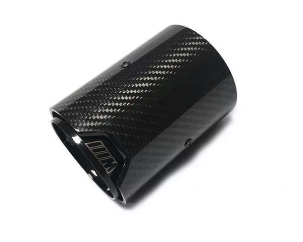 A glossy black carbon fiber exhaust tip lies against a white background, its cylindrical shape adorned with subtle diagonal patterns and screws, featuring an emblem resembling “M” outlined near the edge.