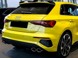 A bright yellow car is parked indoors, featuring twin exhausts and a rear spoiler. The Audi logo and 