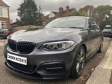 A dark gray BMW car is parked on a residential street. The license plate reads 