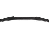 An aerodynamic, black carbon fiber car spoiler sits against a white background, showcasing its sleek, curved design and distinct texture.
