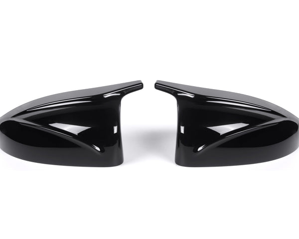 Two sleek black car side mirror covers face each other, reflecting light. They rest on a plain white background, showcasing their glossy finish and aerodynamic design.