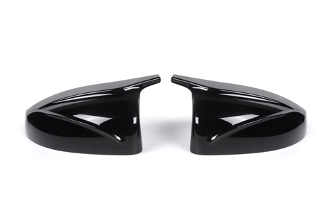 Two sleek black car side mirror covers face each other, reflecting light. They rest on a plain white background, showcasing their glossy finish and aerodynamic design.