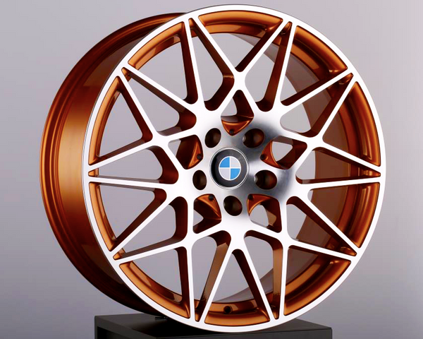 Copper-colored alloy wheel with a complex, geometric spoke design, displaying a BMW logo in the center, placed on a black pedestal against a plain background.