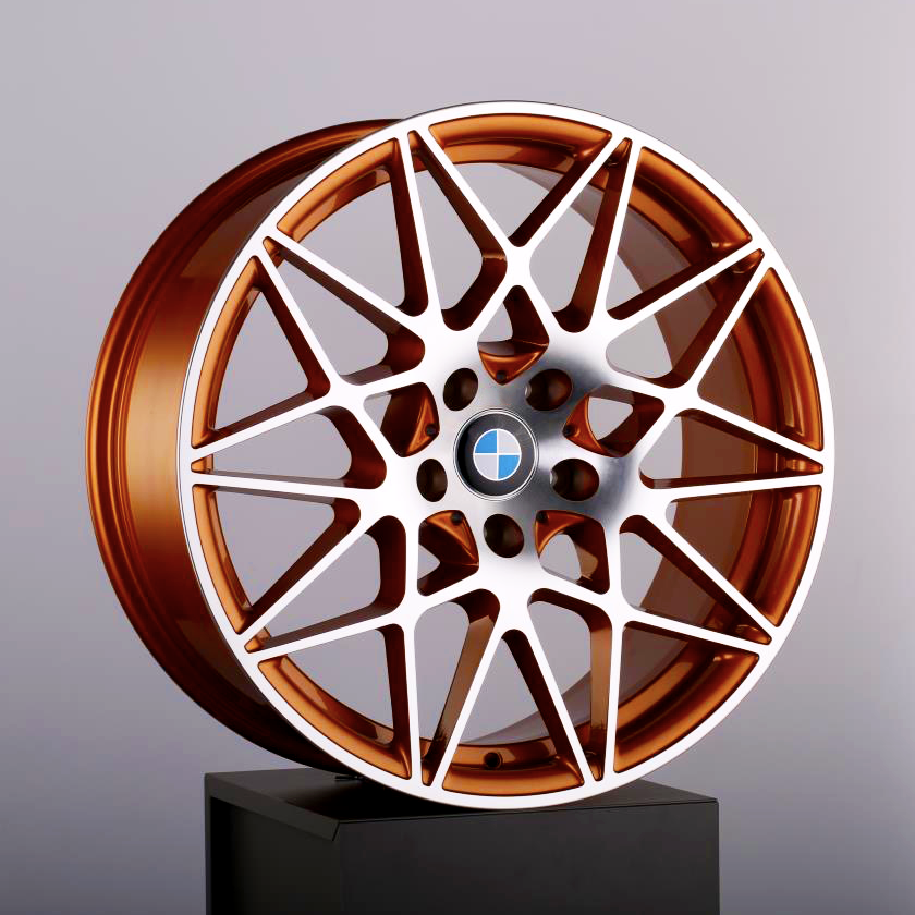 Copper-colored alloy wheel with a complex, geometric spoke design, displaying a BMW logo in the center, placed on a black pedestal against a plain background.