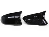 Two black car side mirror covers are displayed on a white background, with one showing an exterior glossy finish and the other revealing attachment points inside.