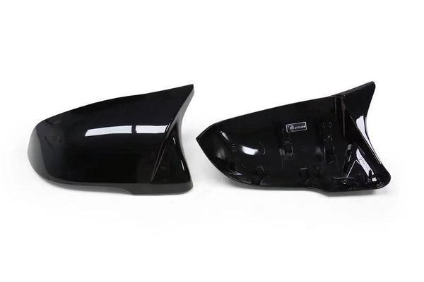 Two black car side mirror covers are displayed on a white background, with one showing an exterior glossy finish and the other revealing attachment points inside.