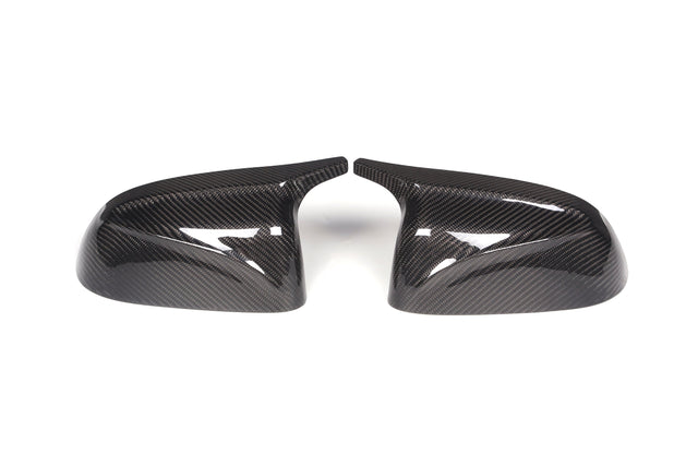 Two carbon fiber side mirror covers face each other, showing a glossy finish and distinct weave pattern, placed on a white background.