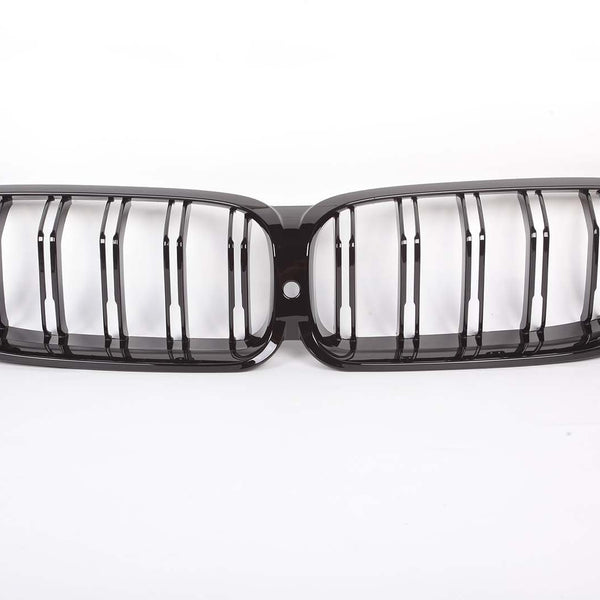 A glossy black car grille, featuring two connected oval sections with vertical slats, is placed on a plain white background.
