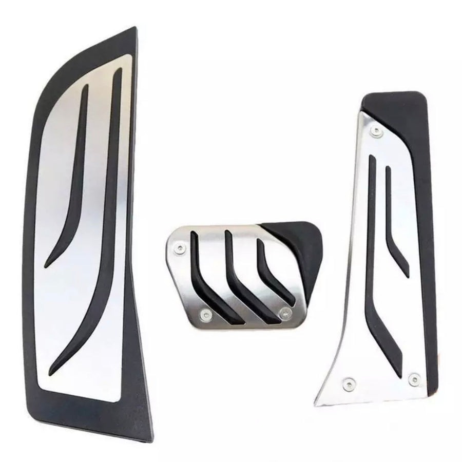Three metallic car pedals with black rubber grips, featuring diagonal grooves, are arranged against a plain white background.