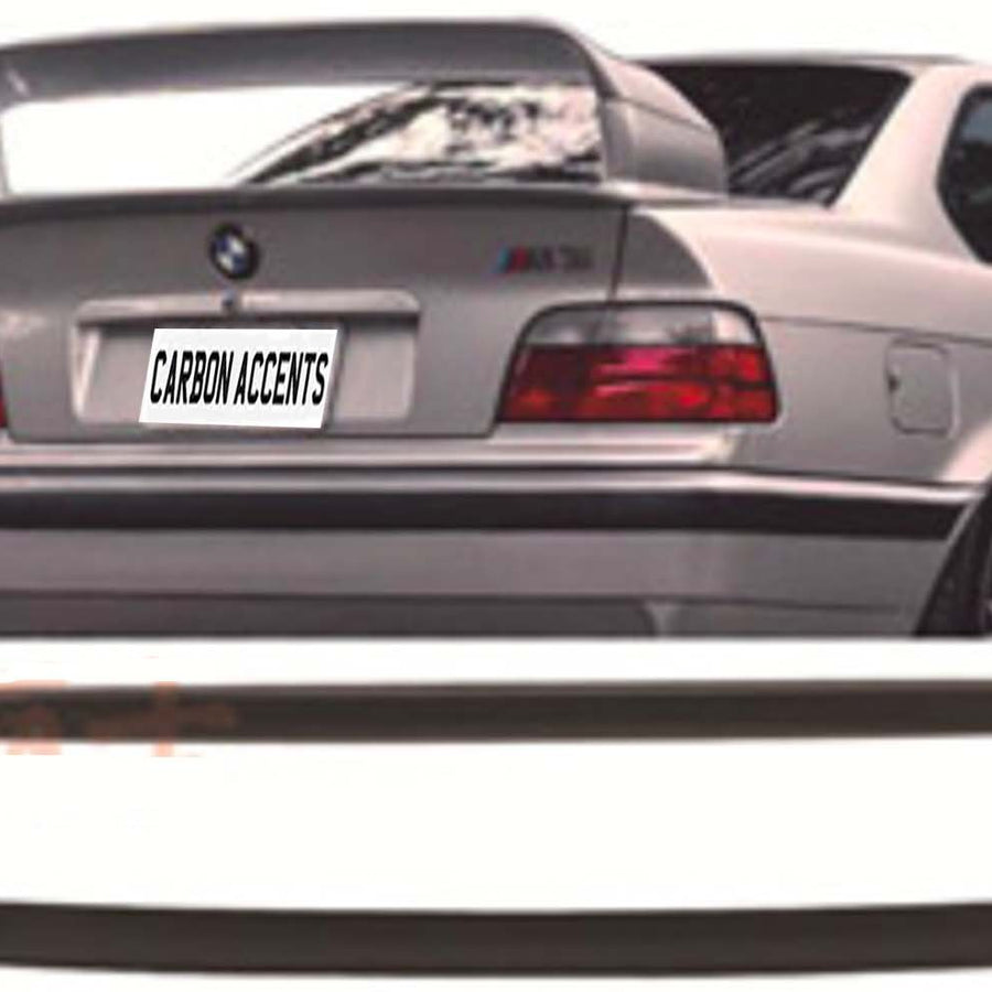 A silver car's rear with a large spoiler and "CARBON ACCENTS" text on the license plate. Below, a detached black car part is displayed in front of a white backdrop.
