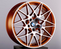 The bronze alloy wheel features an intricate, multi-spoke design, resting on a black pedestal. A blue-and-white circular emblem is at the center, set against a plain background.