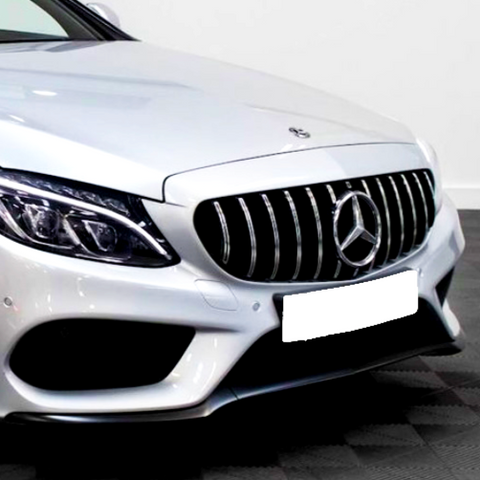 A silver car with a prominent grille and emblem is parked on a patterned floor. The headlights are sleek and angular, highlighting the car's modern design in a well-lit space.