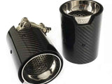 Two carbon fiber exhaust tips with a metallic interior, one upright, the other lying down showing adjustable clamps. Both feature a 