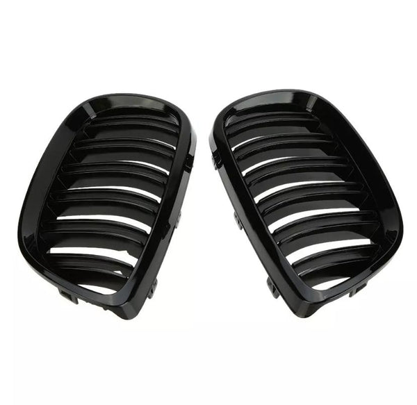 Two black, glossy car grilles with parallel slats are positioned side by side against a plain, white background, likely intended for vehicle front-end installation.