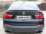 A black BMW X4 with visible taillights is parked on gravel. The license plate reads 