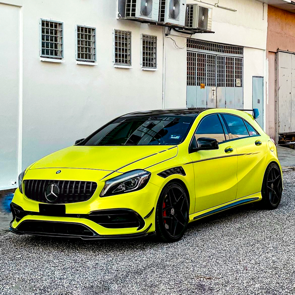 A bright yellow sports car, parked in front of a white building with air conditioning units mounted above, sits on a gravel surface, showcasing sleek, modern styling and black accents.