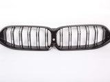 A black car grille with parallel vertical slats, forming a dual-kidney shape, is centered on a plain white background.