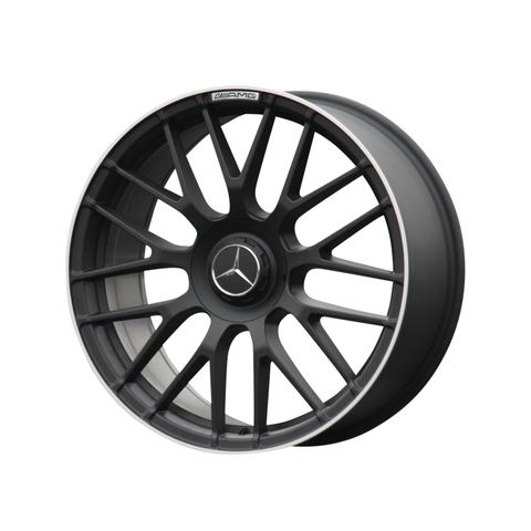 A black alloy car wheel with multiple thin spokes is positioned upright. The center features a three-pointed star emblem. "AMG" text is visible near the rim on a white background.
