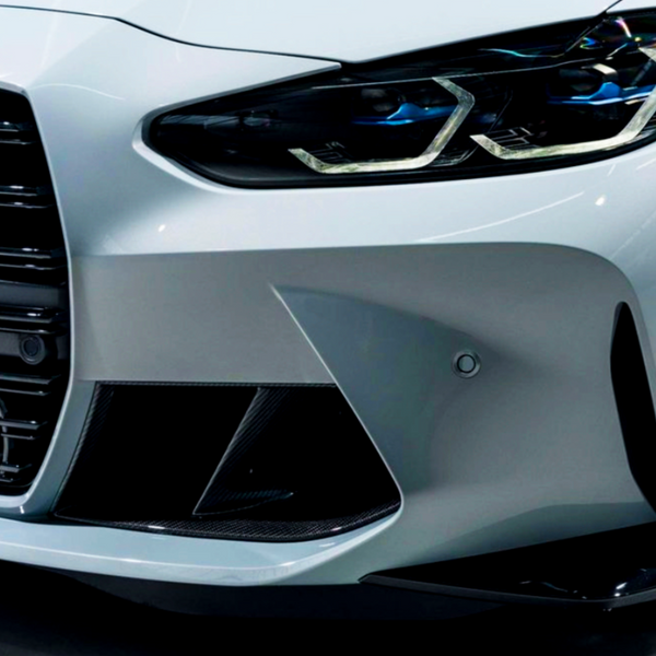 A modern car's front end with sleek headlights and prominent grille design, highlighted by a smooth, glossy surface in a well-lit, indoor environment.