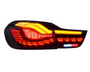 A car tail light emits bright red and amber lights, featuring modern, segmented design elements against a white background.