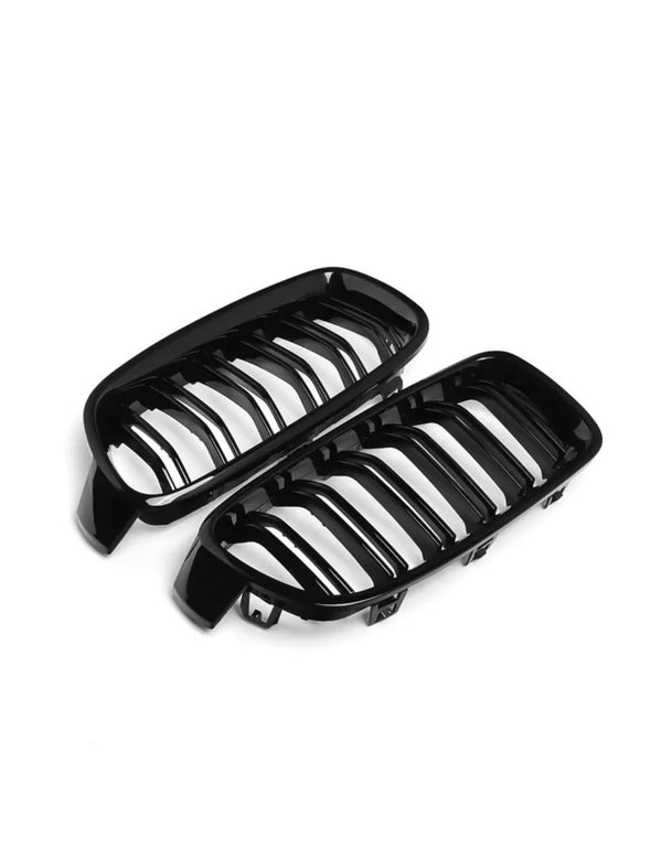 Black car grille with horizontal slats, arranged in a pair, lies on a plain white background, suggesting an automotive accessory context.