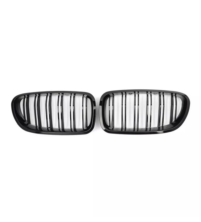 Two black, oval car grilles with vertical slats are positioned side by side against a plain white background.