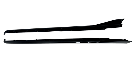 Two long, black vehicle side skirts are positioned horizontally on a white background, each displaying a sleek, aerodynamic design with smooth, glossy surfaces.