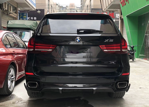 A black BMW X5 is parked beside a red car in an urban alley. The area is surrounded by buildings, with some signs in Chinese characters visible in the background.
