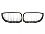 Two black car grille inserts with vertical slats are placed side by side against a plain white background, suggesting a symmetrical design typical of vehicle front ends.