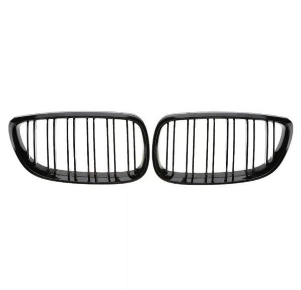 Two black car grille inserts with vertical slats are placed side by side against a plain white background, suggesting a symmetrical design typical of vehicle front ends.