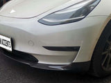 A white car with carbon fiber accents is parked on an asphalt surface. The license plate reads 