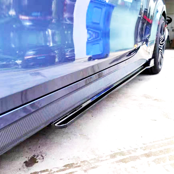 A blue car with a glossy surface reflects nearby objects, including a blue container, parked on a concrete floor in a garage.