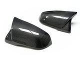 Two glossy, dark carbon fiber side mirror covers, positioned on a plain white background, showcasing their sleek, aerodynamic design and intricate pattern.