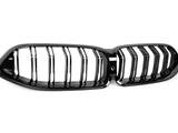 A black car front grille with vertical slats, featuring a kidney-shaped design. It rests on a plain white background, highlighting its glossy finish and sleek appearance.