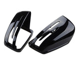 Two glossy black car mirror covers with sleek, aerodynamic slits are placed side by side against a plain white background.