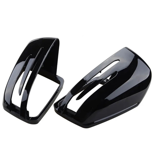 Black plastic mirror covers with aerodynamic openings lie on a white background, positioned side by side, designed to fit over vehicle side mirrors for protection and style enhancement.