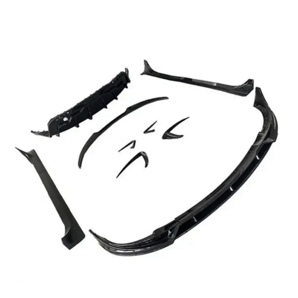 Several black car body kit components are spread out, including a front splitter, side skirts, and bumper lip, arranged on a plain white background.
