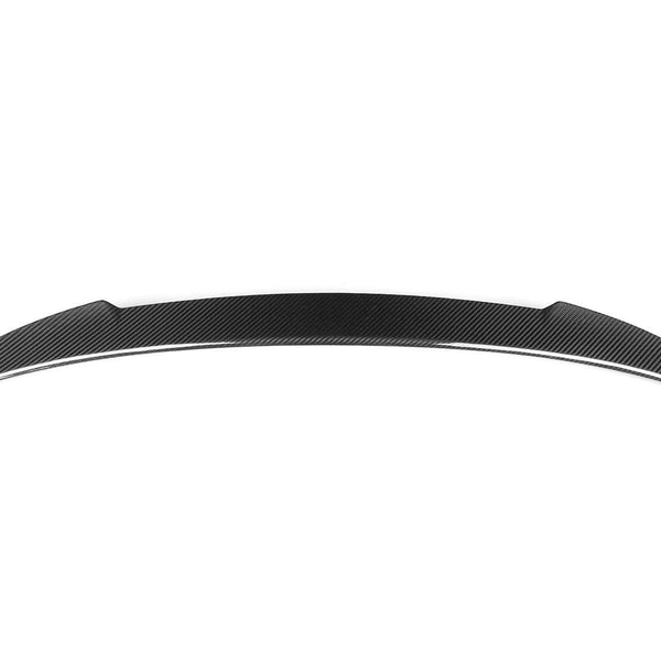 A sleek, curved car spoiler, likely made of carbon fiber, rests against a plain white background. Its aerodynamic design features pointed ends and a subtle pattern, suggesting high-performance or racing use.