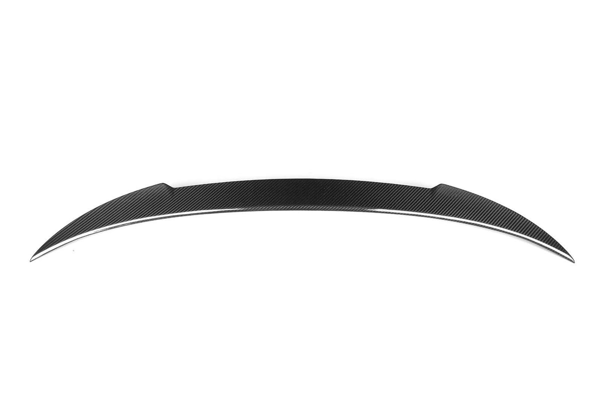 A sleek, curved car spoiler, likely made of carbon fiber, rests against a plain white background. Its aerodynamic design features pointed ends and a subtle pattern, suggesting high-performance or racing use.