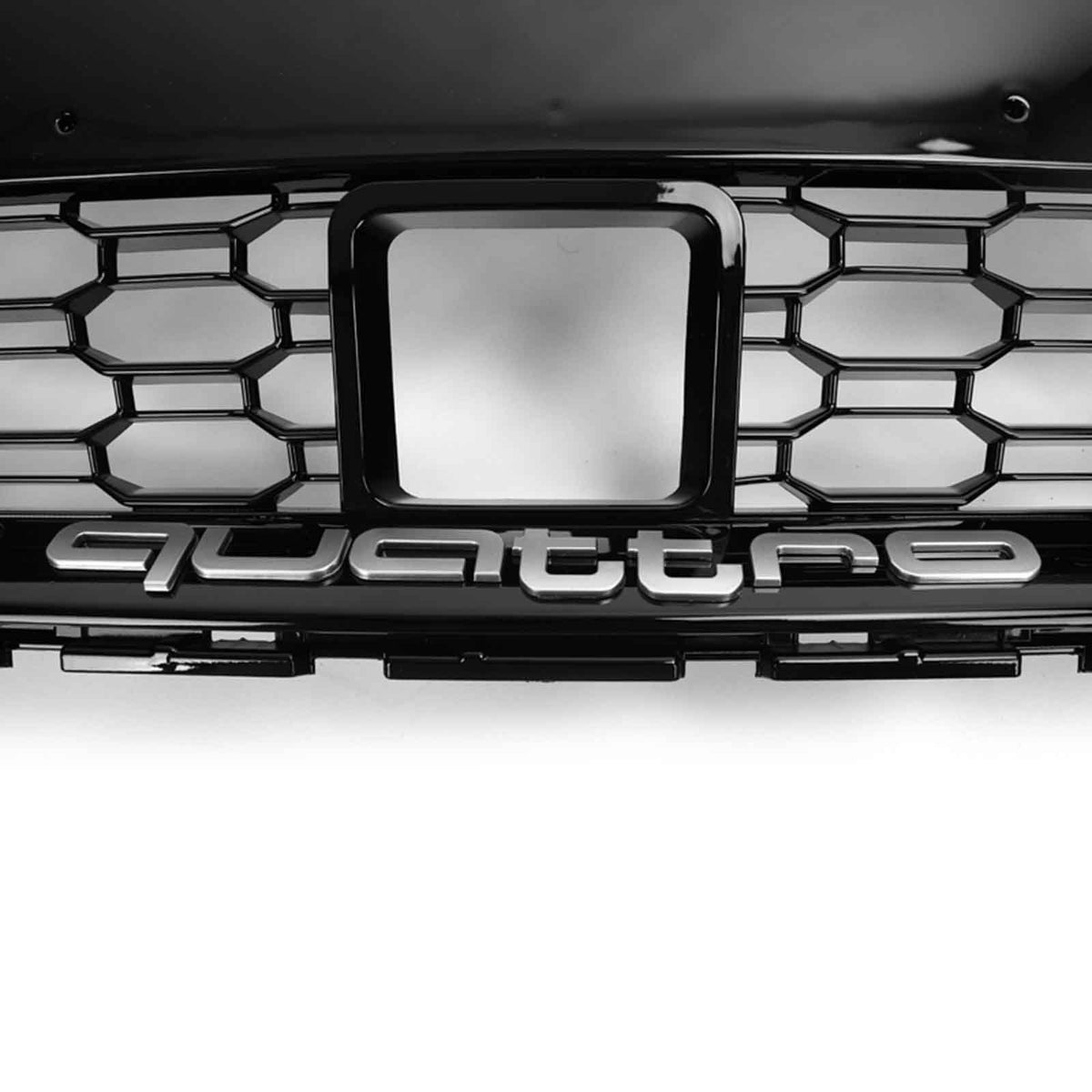A black car grille with a hexagonal pattern displays the word "quattro" in silver letters. The context is a close-up view focused on the central badge area.