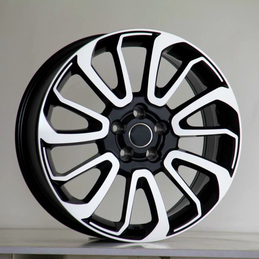 A black and white car wheel rim with a multi-spoke design is upright on a plain surface, set against a neutral background.