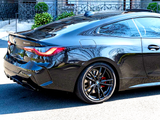 A sleek black BMW car is parked on a sunlit street, showcasing red brake calipers and reflective bodywork. Text reads 